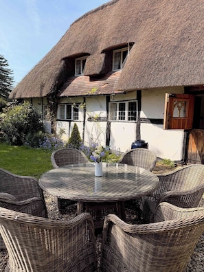 A thatched-roof house with a garden and wicker furniture. - Mesopotamia Cottage Country Hideaway (Clifton Hampden)