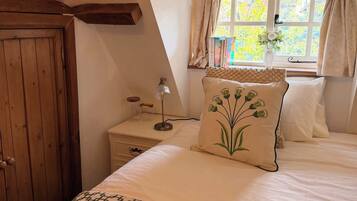 Un dormitorio con cama, mesita de noche, lámpara, ventana con cortinas y puerta de madera.