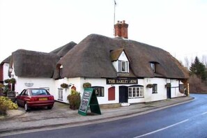 A traditional thatched-roof building with a sign reading 'The Barley How.'