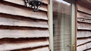 Une façade en bois avec un bardage horizontal et une porte en verre dotée d’un système coulissant.