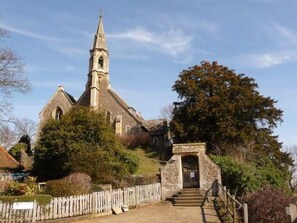 Une église dotée d’un clocher imposant, d’une entrée en pierre et d’une clôture en bois en premier plan.