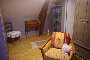 Een kamer met een houten stoel, een klein tafeltje, een kast en een trap.