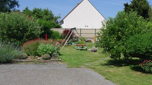 Ein Garten mit einer Schaukel, einem Picknicktisch und einem Gebäude im Hintergrund.
