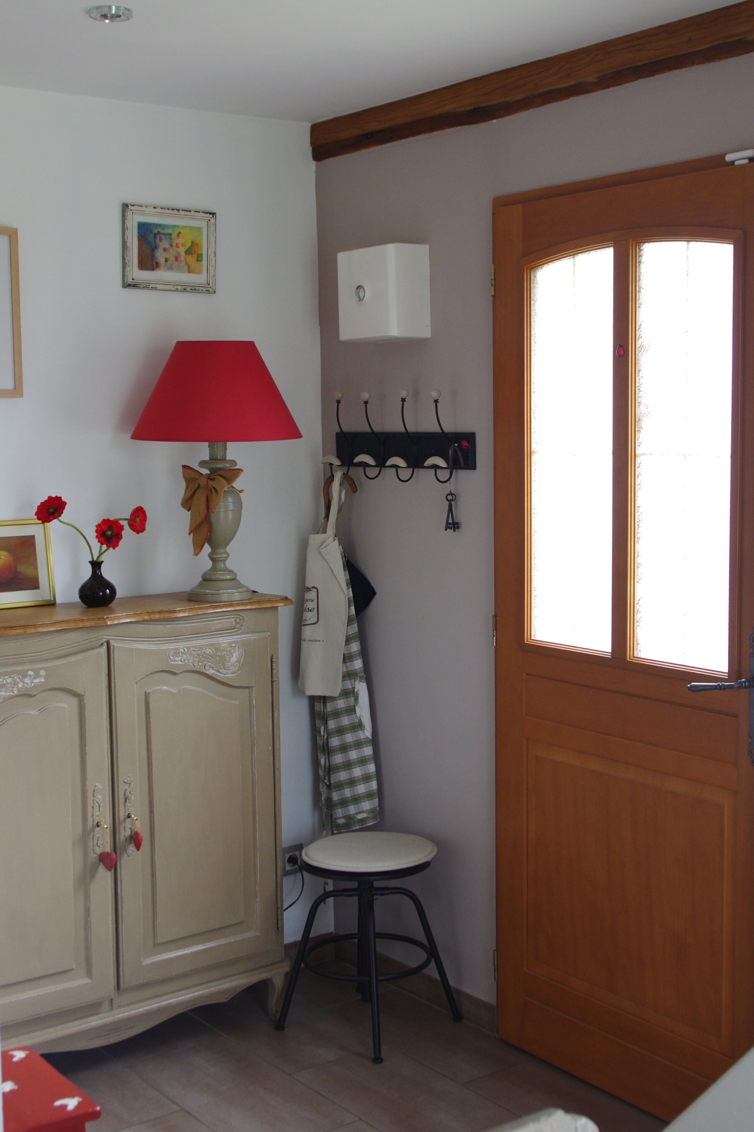 Ein Zimmer mit Holztür, roter Lampe, Schrank und Kleiderständer.