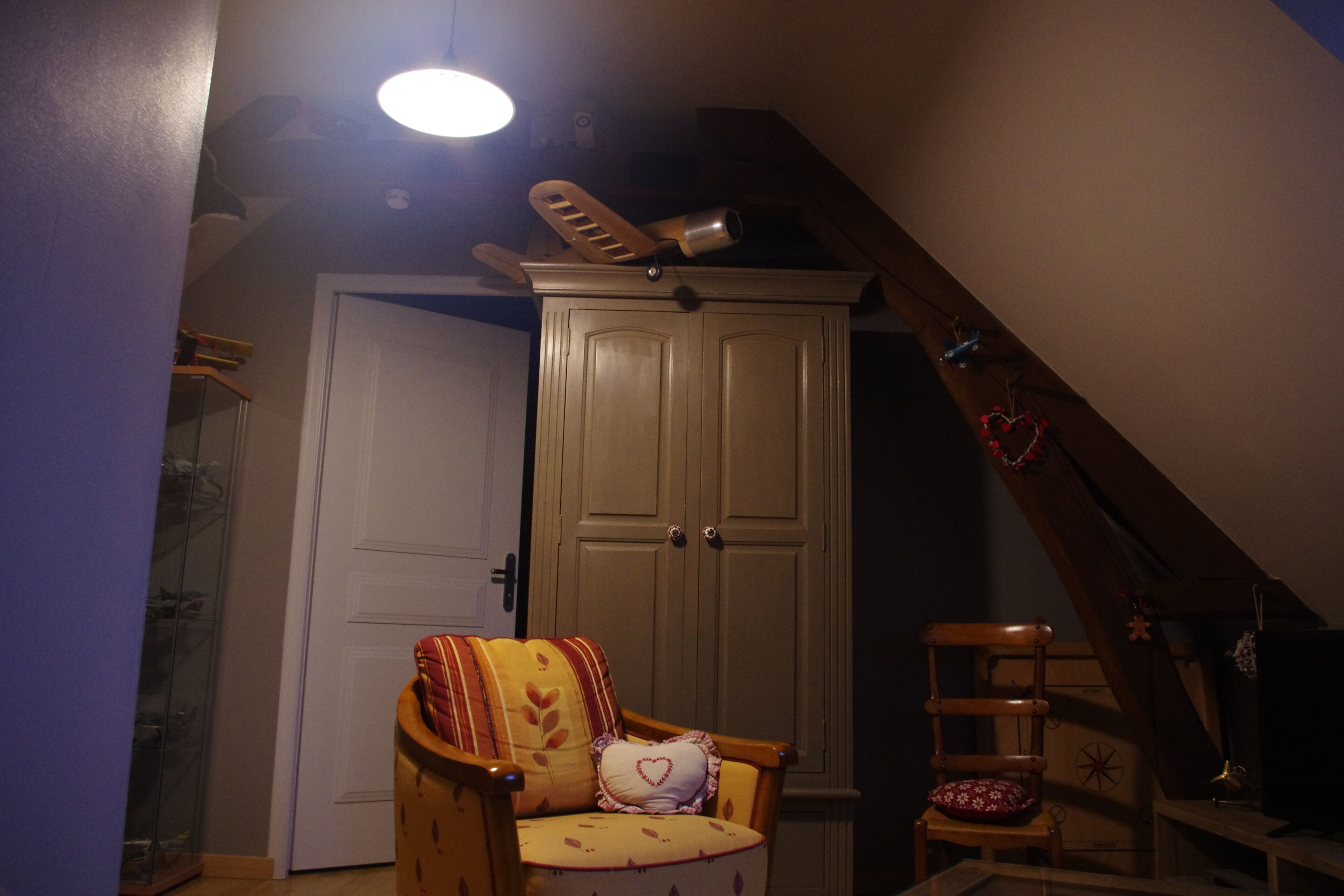 Una habitación con una silla de madera, una puerta blanca y un armario de madera.