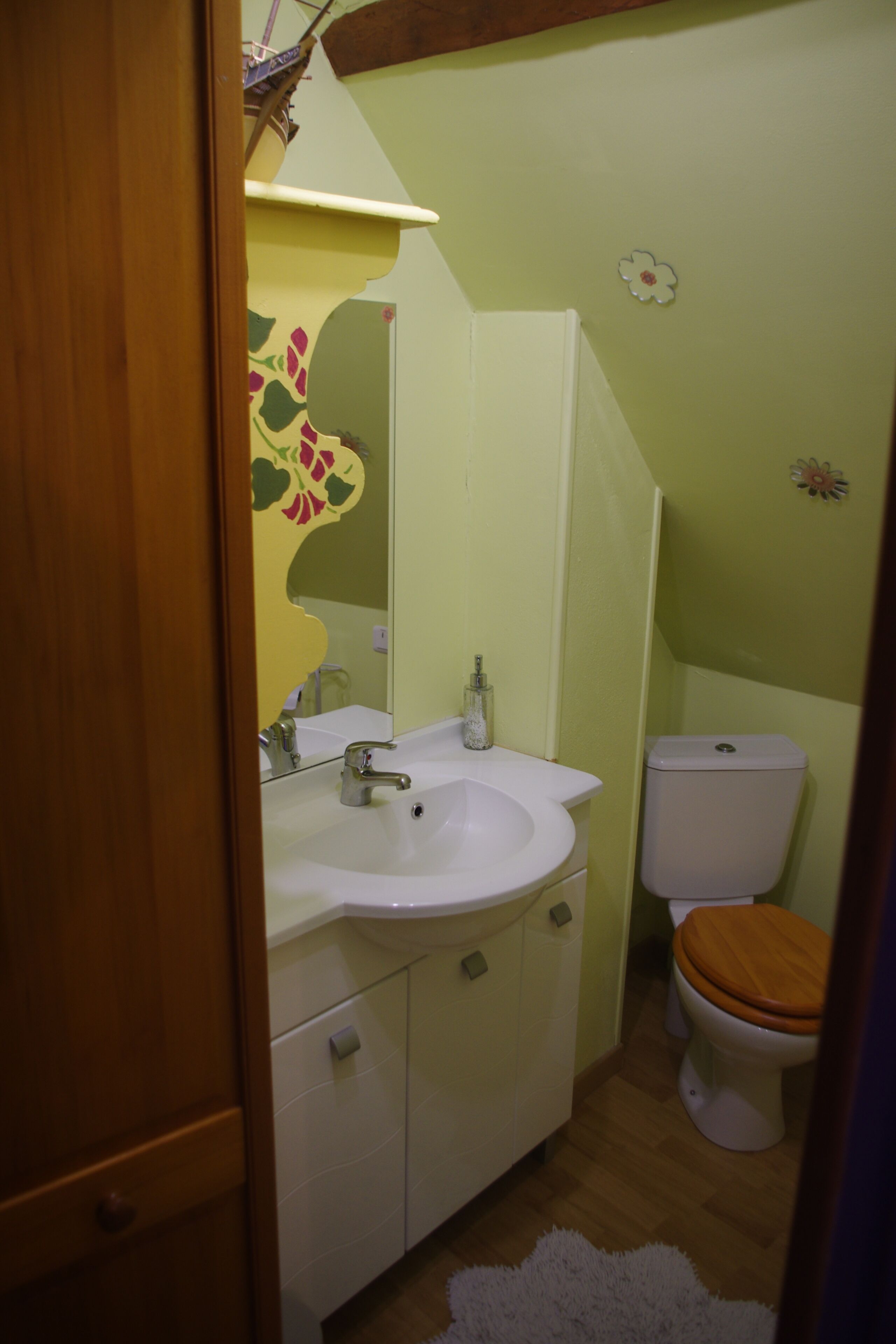 Un bagno con lavandino, specchio, WC e una porta in legno.