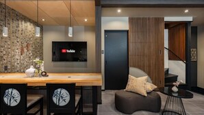 A modern interior with a wooden dining table, chairs, a sofa, and a TV mounted on the wall. - JAPAVISTA Hinata (KONOHANA WARD)