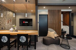 A modern interior with a wooden dining table, chairs, a sofa, and a TV mounted on the wall. - JAPAVISTA Hinata (KONOHANA WARD)