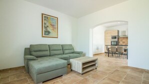 Ein Wohnzimmer mit einem Ecksofa, einem Couchtisch und einem Gemälde an der Wand.
