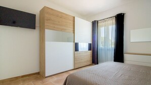 Ein Schlafzimmer mit einem Bett, einem Kleiderschrank und einem fenster mit Vorhängen.