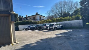 A parking area with multiple cars, a building with a chimney, and a clear sky. - Great location with parking, and easily accessible from the airport too! (Treviso)