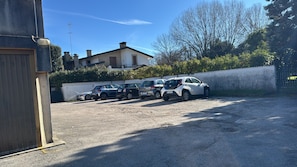 Ein Parkplatz mit mehreren Autos, ein Gebäude mit Schornstein und einem klaren Himmel.