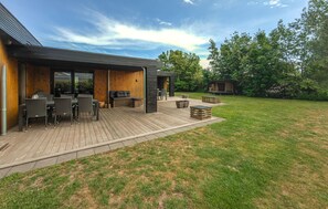 Ein modernes Haus mit Terrasse, Sitzgelegenheit im Freien und einem Garten.