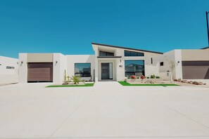 Une maison moderne à deux étages, dotée d’un garage, d’une allée et d’une pelouse bien entretenue.