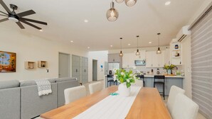 A modern kitchen with white cabinets, a dining table with chairs, and a ceiling fan. - Casa Luna  By FMI Rentals (Puerto Peñasco)