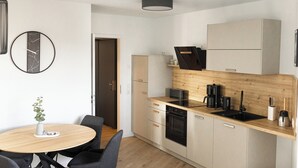 Une cuisine moderne dotée d’un plan de travail en bois, d’appareils électroménagers intégrés et d’une table de salle à manger ronde, accompagnée de chaises.