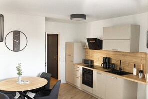 Eine moderne Küche mit Holzarbeitsplatte, eingebauten Geräten und einem runden Esstisch mit Stühlen.