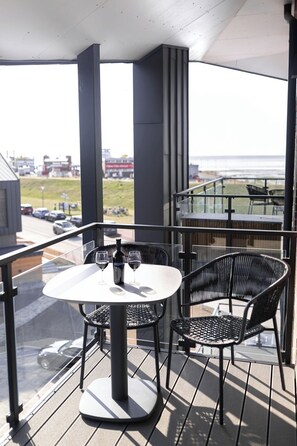 A balcony with a table and chairs, a bottle of wine, and a glass of wine. - The View A14 Langeneß-Kiek – Sea View, Shared Sauna, Elevator, Garden Furniture (Dagebüll)