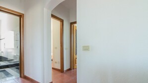 A hallway with tiled flooring, wooden doors, and a light switch on the wall. - Spacious and comfortable 142 square meters apartment, perfect for six people, located on the first floor of a two-family building.The property is located in a quiet area surrounded by nature, ensuring a relaxing stay. A car is recommended.The accommodati (Arzachena)