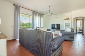 A living room with a sofa, a television, and a kitchen area. - Spacious and comfortable 142 square meters apartment, perfect for six people, located on the first floor of a two-family building.The property is located in a quiet area surrounded by nature, ensuring a relaxing stay. A car is recommended.The accommodati (Arzachena)