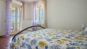 A bedroom with a bed, a chair, a dresser, and a window with curtains. - Spacious and comfortable 142 square meters apartment, perfect for six people, located on the first floor of a two-family building.The property is located in a quiet area surrounded by nature, ensuring a relaxing stay. A car is recommended.The accommodati (Arzachena)