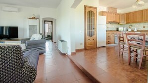 A living room with a sofa, TV, and a dining area with chairs and a table. - Spacious and comfortable 142 square meters apartment, perfect for six people, located on the first floor of a two-family building.The property is located in a quiet area surrounded by nature, ensuring a relaxing stay. A car is recommended.The accommodati (Arzachena)