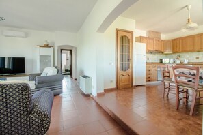 Una sala de estar con sofá, televisor y un comedor con sillas y mesa.