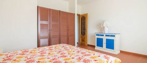 Un dormitorio con cama, armario, aparador y puerta.