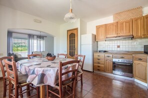 A dining area with a table set for four, wooden chairs, a bowl, and a chandelier. - Spacious and comfortable 142 square meters apartment, perfect for six people, located on the first floor of a two-family building.The property is located in a quiet area surrounded by nature, ensuring a relaxing stay. A car is recommended.The accommodati (Arzachena)