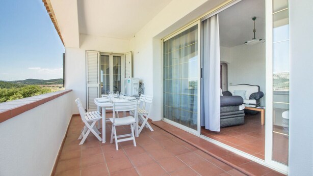 A balcony with a table and chairs, a sliding glass door leading to a bedroom, and a view of the landscape. - Spacious and comfortable 142 square meters apartment, perfect for six people, located on the first floor of a two-family building.The property is located in a quiet area surrounded by nature, ensuring a relaxing stay. A car is recommended.The accommodati (Arzachena)