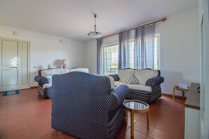 Un salon comprenant un ensemble de canapés, un fauteuil à motifs, une petite table ronde et une fenêtre avec des rideaux.
