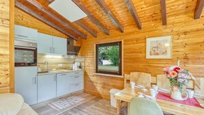 A wooden cabin interior with a kitchenette, dining area, and a window with a view.