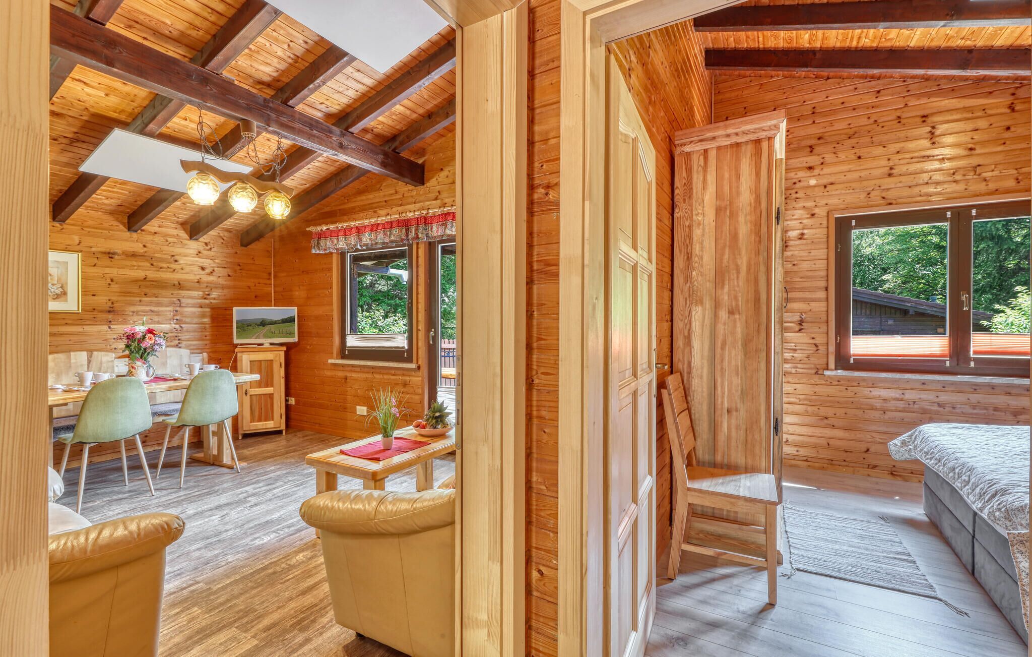 L’intérieur d’un chalet en bois comprend un coin repas, un téléviseur et un lit.