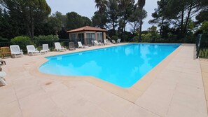 A rectangular swimming pool with a tiled deck, surrounded by lounge chairs and a small pavilion. - Apartment Gioia: Your Beachfront Paradise with Pool (Saint Raphael)