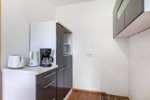 Een kleine keuken met een broodrooster, koffiezetapparaat en magnetron.