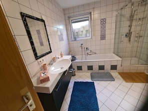 Ein Badezimmer mit Waschbecken, Spiegel, Badewanne und Dusche.