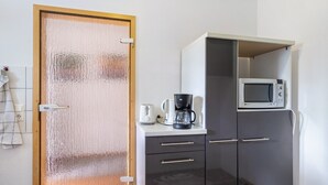 Et tekøkken med mikroovn, kaffemaskine og et skab.