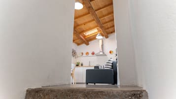 Una cocina moderna con vigas de madera, un área de comedor con un sofá y una pequeña mesa.
