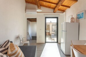 A modern kitchen with a refrigerator, a dining table, and a bench. - Casa Steinmelker (Seneghe)