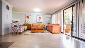 Uma sala de estar com sofá, mesa de centro e uma janela grande com vista.
