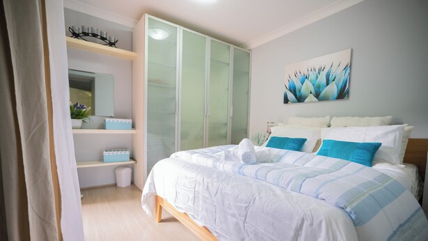 Quarto com cama, guarda-roupa, espelho e uma obra de arte na parede.