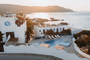 A hotel with a pool, lounge chairs, and a view of the sea.