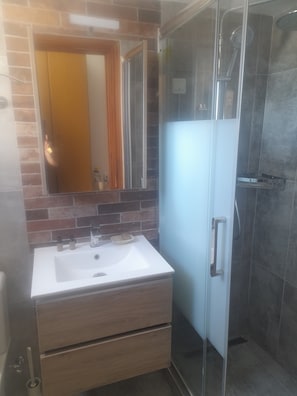 Ein Badezimmer mit Waschbecken, Spiegel und Dusche.