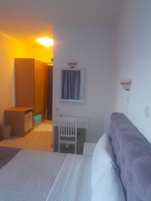 A hotel room with a bed, a desk, a chair, a wardrobe, and a bathroom.