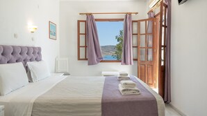 A hotel room with a bed, a view of the sea, and a wooden door.