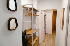 Ein schmaler Flur mit einer Holzregaleinheit, einem Spiegel und einer Tür zu einem anderen Raum.