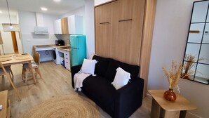 Een moderne woonruimte met een bank, een eettafel, een keukenhoek en een grote inloopkast.