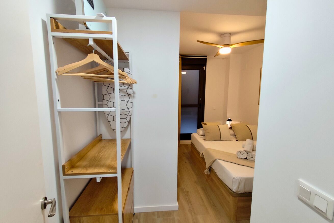 Une chambre à coucher avec un lit, un ventilateur de plafond et une armoire avec des étagères.