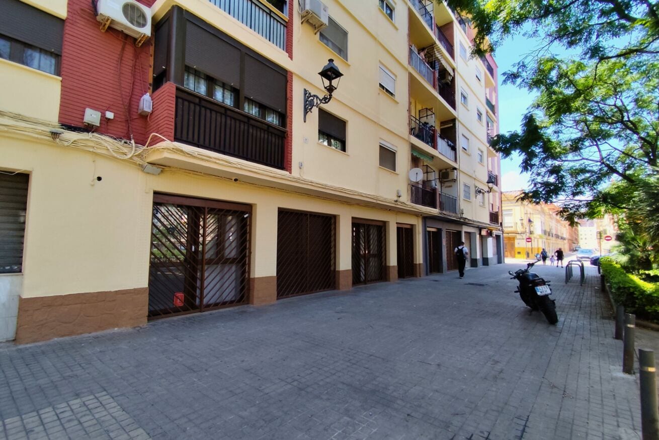 A multi-story building with balconies, a paved street, and a parked motorcycle.