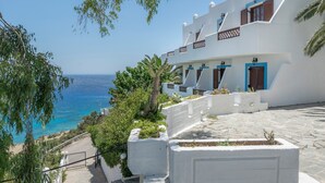 Un edificio blanco con detalles azules, una escalera de piedra y vista al mar.
